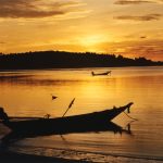 Picture of fishing boat with sunset sky behind it.